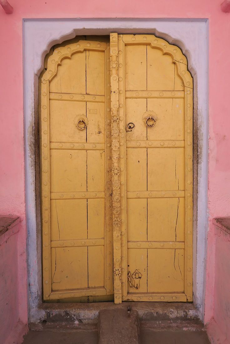 A yellow door set into a pink wall