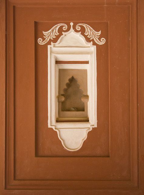 A weathered orange door with ornamental detail